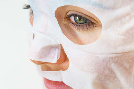 Woman with sheet mask on her face. Girl taking care of skin. Beauty treatment. Skincare.の写真素材