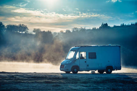 Caravan camping on lake shore in Portugal. Camper trip in autumn time. Foggy misty peace morning.の写真素材