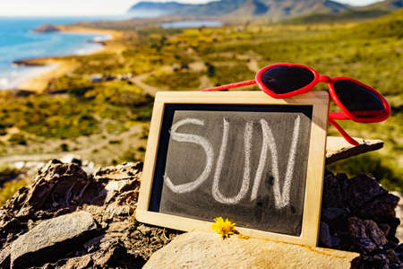 Black board with word sun against spanish sea coast. Landscape of Calblanque Park in Murcia Spain. Travel, vacation and prevention of vitamin D deficiency.の写真素材