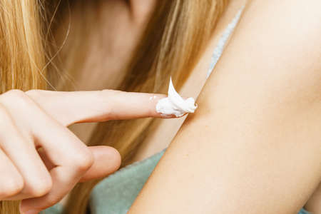 Skincare spa wellbeing. Woman wearing bra underwear taking care of her dry skin, applying moisturizer body cream.の写真素材