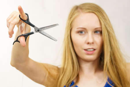 Young woman holding special chunking shears, tool for work of hairdresser. Coiffure hairstyle and haircut.の写真素材