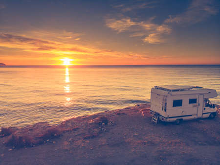 Camper car rv camping on coast sea shore at sunrise. Adventure, travel with mobile home.