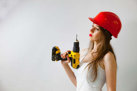 Young woman using power driil for work at home. Girl working at flat remodeling. Building, repair...