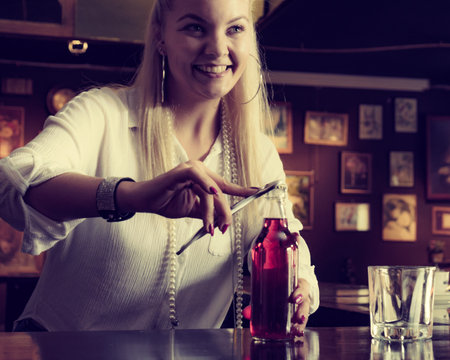 Female working at the bar counter, opening red bottle lemonadeの写真素材