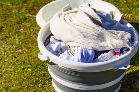 Doing laundry on vacation trip. Buckets with washing clothes outdoors on nature.の写真素材