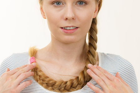 Blonde girl with long braid hair around the neck. Haircare, hairstyling.