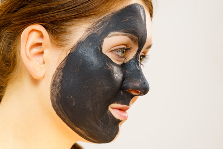 skincare. Woman with charcoal facial mask, deep cleanser on face. Beauty, spa and acne treatment. side viewの写真素材