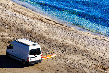 Campervan rv and iInflatable stand up board on beach sea shore. Van life, holidays in Spain. Recreation, adventure sports and activities. View from aboveの写真素材