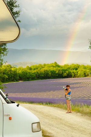 camper trip. Woman taking travel picture from rainbow over lavender blooming purple field, Provence in France. Holidays, vacation with mobile home.の写真素材