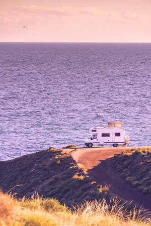 Camper rv with tilt solar photovoltaic panels on roof camping on cliff sea shore in wintertime. Mediterranean region of Villaricos, Costa Almeria in Andalusia, Spainの写真素材