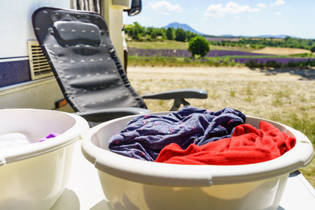 Doing laundry on vacation trip. Bowls with clothes at caravan vehicle. Camping on nature.の写真素材