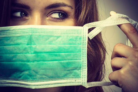 Woman using protective face mask, covering mouth. Coronavirus prevention. Healthcare medical hygiene concept.の写真素材