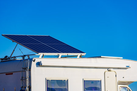 Camper rv with tilt solar photovoltaic panels on roof camping on nature in wintertime. Blue sky with copy space.の写真素材