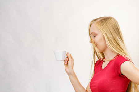 Blonde long hair woman with heart shaped coffee cup. Time to wake up, switching on. copy space.の写真素材
