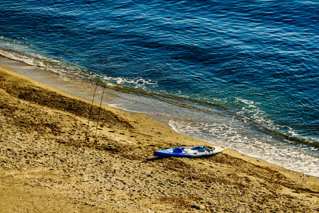 Boats kayaks and fishing rods on sea shore beach.の写真素材