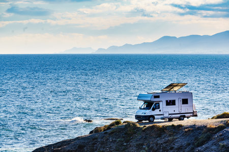 Camper rv with tilt solar photovoltaic panels on roof camping on cliff sea shore in wintertime. Mediterranean region of Villaricos, Costa Almeria in Andalusia, Spainの写真素材
