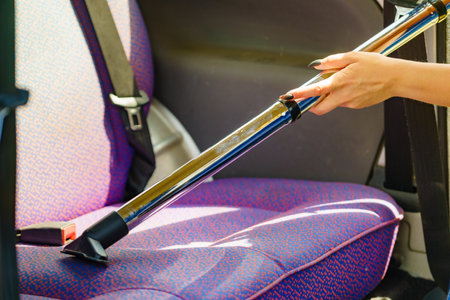 Woman hoovering seat of car. Auto interior cleaning with vacuum cleaner.の写真素材