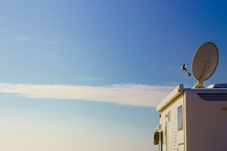 Satellite dish on the roof of camper car against blue sky. TV connection. Travel holidays in motor home.の写真素材