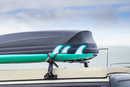 Car equipped with surfboard and trunk or cargo box on roof. Activity, holidays trip. Accessories for...