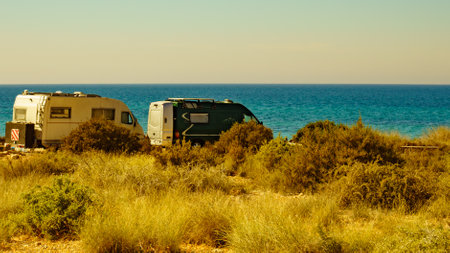 Camper and van recreational vehicles on mediterranean coast in Spain. Camping on nature beach. Holidays and travel in motor home.の写真素材