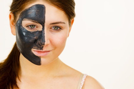 skincare. Woman with charcoal facial mask, deep cleanser on half face. Beauty, spa and acne treatment.の写真素材