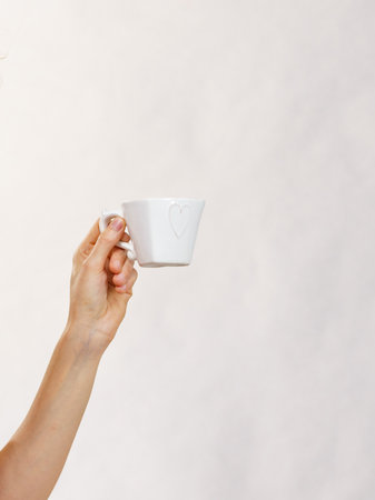 Female hand with heart shaped coffee cup. Time to wake up, switching on. Copy space.の写真素材