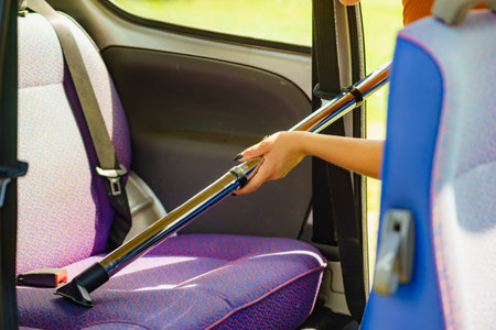 Woman hoovering seat of car. Auto interior cleaning with vacuum cleaner.の写真素材