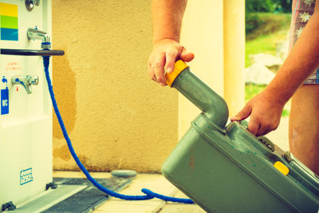 Man emptying caravan tank toilet cassette in dump point during road trip in France. Dumping station for recreational vehicle. camper service.の写真素材