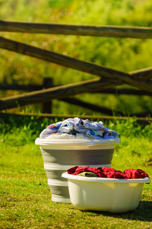 Doing laundry on vacation trip. Buckets with washing clothes outdoors on nature.の写真素材