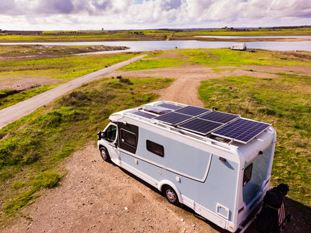 Aerial view of camper with many solar photovoltaic panels on roof camping on lake shore in Portugal. Renewable free energy. Caravan holidays.の写真素材