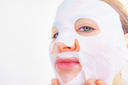 Woman with sheet mask on her face. Girl taking care of skin. Beauty treatment. Skincare.の写真素材
