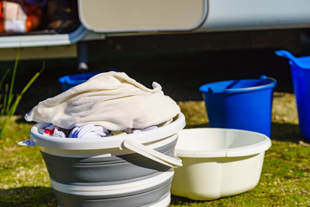Doing laundry on vacation trip. Buckets with washing clothes outdoors on nature.の写真素材