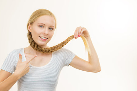 Blonde girl with long braid hair. Haircare, popular hairstyle.の写真素材