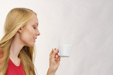 Blonde long hair woman with heart shaped coffee cup. Time to wake up, switching on. copy space.の写真素材