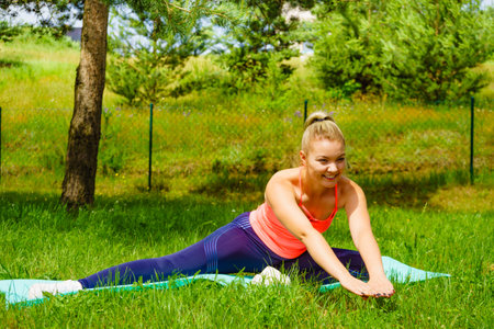 Woman doing exercises outdoors in garden. Workout sports and training. Healthy lifestyle, well being, home gym.の写真素材