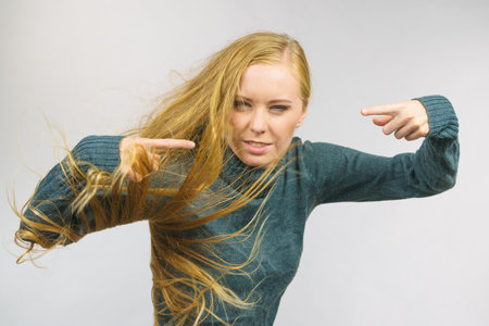 Angry young woman pointing with fingers. Frustrated face expression, hair blowing.の写真素材