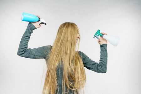 Young female messy long blonde hair holding bottle, applying hair spray.の写真素材