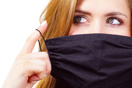 Woman using black protective reusable face mask, covering mouth. Coronavirus prevention. Health and safety.の写真素材