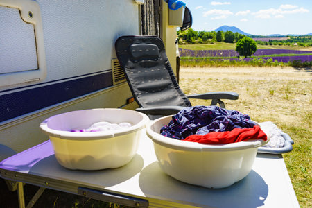 Doing laundry on vacation trip. Bowls with clothes at caravan vehicle. Camping on nature.の写真素材