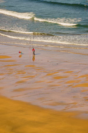Fisherman angler with fishing rod on sea shore.の写真素材