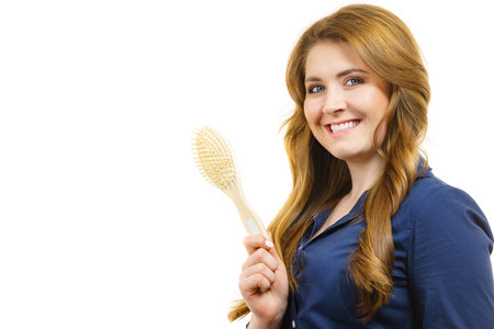 Young woman combing long healthy brown hair, using brush. Haircareの写真素材