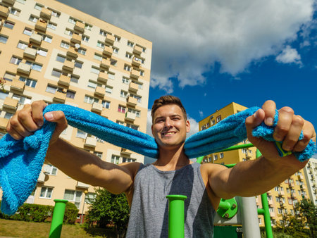 Handsome guy relaxing after outdoor workout. Fit man feeling healthy, enjoying sun. Exercising on public gym equipment in the open air.の写真素材