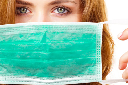 Woman using protective face mask, covering mouth. Coronavirus prevention. Healthcare medical hygiene concept.の写真素材