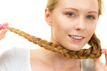 Blonde girl with long braid hair. Haircare, hairstyling, feminine style.の写真素材