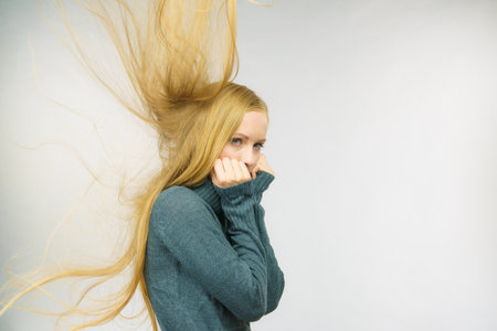 Sad melancholy young woman with blowing long blonde hair.