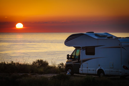 Sun rising over sea horizon, day break and caravan parking on beach sea shore. Travel with mobile home.の写真素材