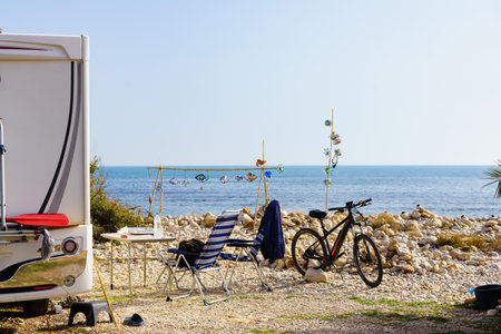Caravan with camp chairs on mediterranean coast, Spain. Wild camping on the beach. Holidays and traveling in motorhome.の写真素材