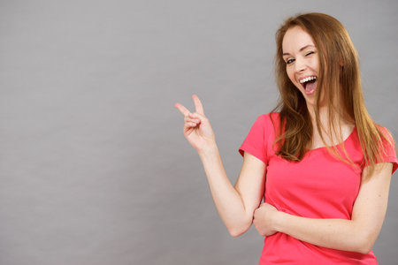 Young happy excited woman winking, doing victory gesture sign. Satisfaction success and celebrating.の写真素材