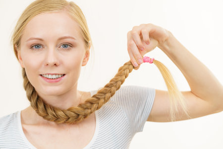 Blonde young woman with long braid hair around the neck. Haircare, braided hairstyles.の写真素材