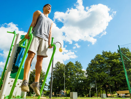 Young man doing exercises on the public gym equipment in the open air.の写真素材